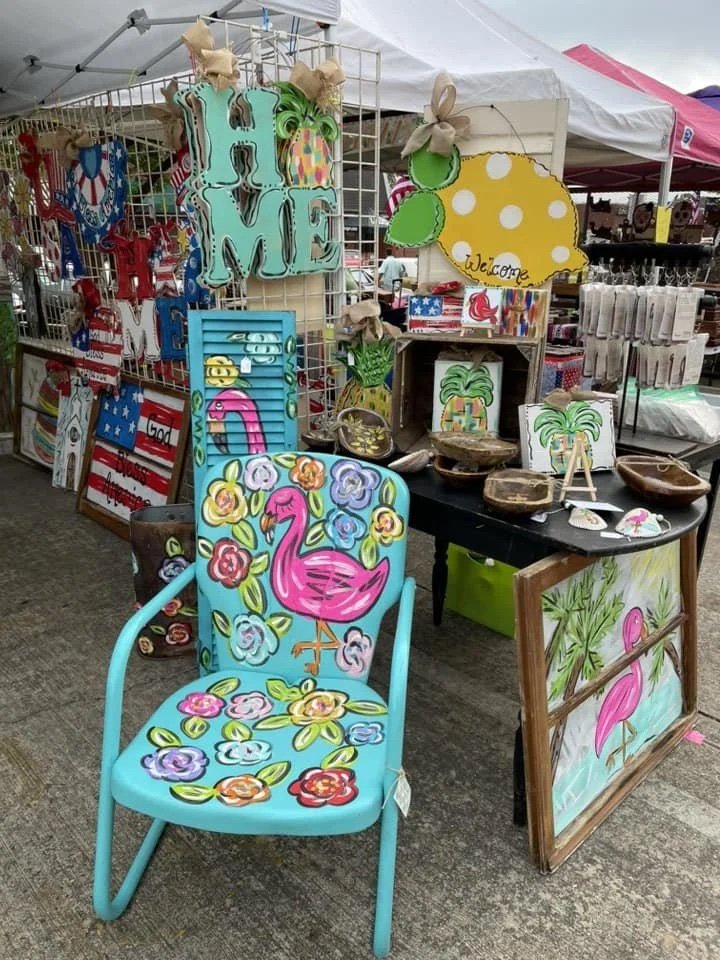 A Morehouse May Madness vendor booth with a hand-painted teal chair with a pink flamingo and painted signs